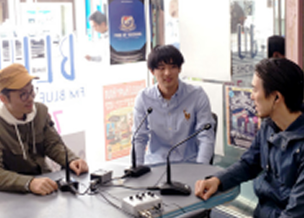 ラジオ収録のような環境で、3人の男性がテーブルを囲んで対話している様子。マイクを前に平和や社会について語り合っている