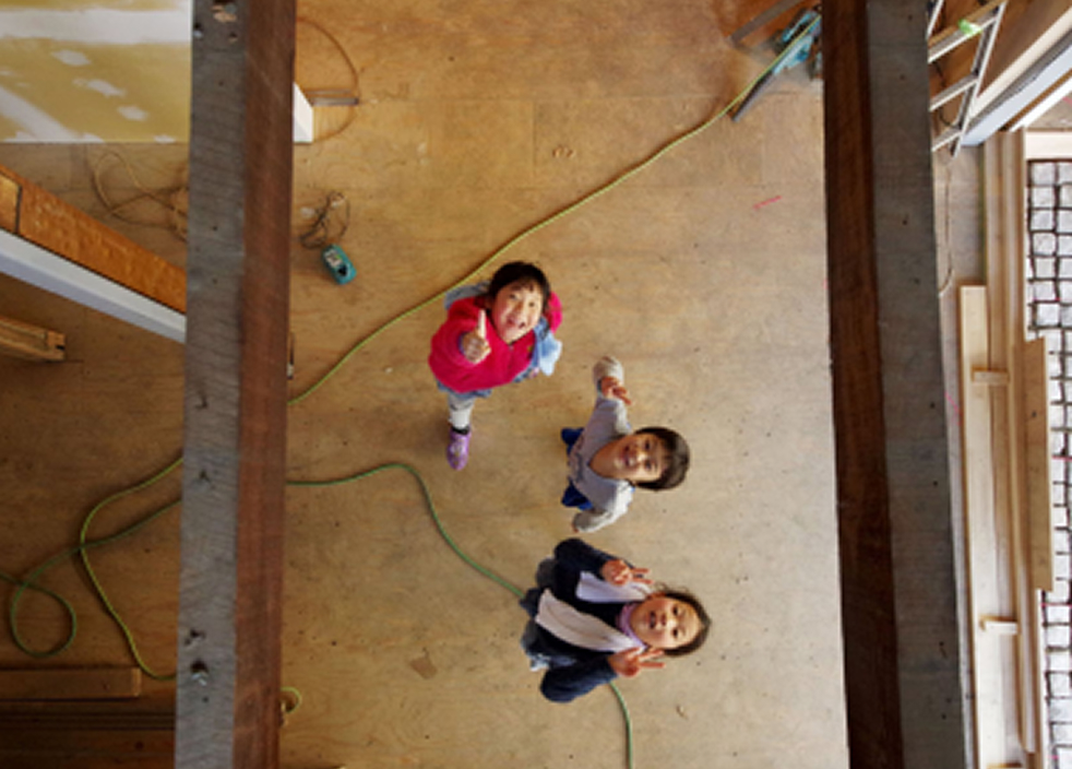 古民家のリノベーション作業中、上から見下ろした視点で3人の参加者が笑顔で手を振っている様子