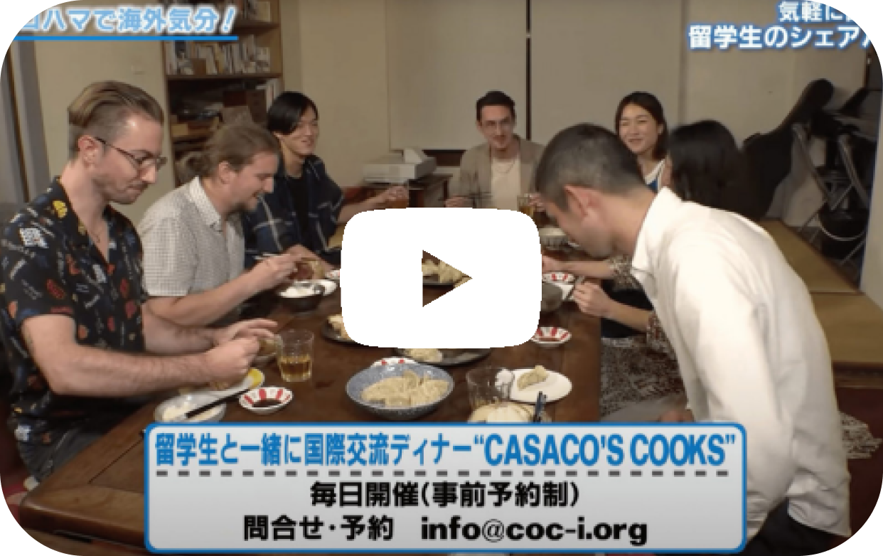 食卓を囲んで留学生と日本人が一緒に料理を楽しみながら会話をしている様子。国際交流イベントの風景
