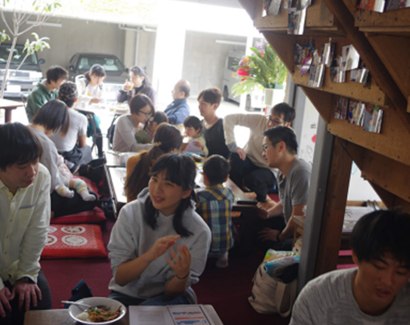 多くの人が座卓を囲んで食事を楽しんでいる様子。室内で国際交流イベント『世界の朝ごはん』が行われている