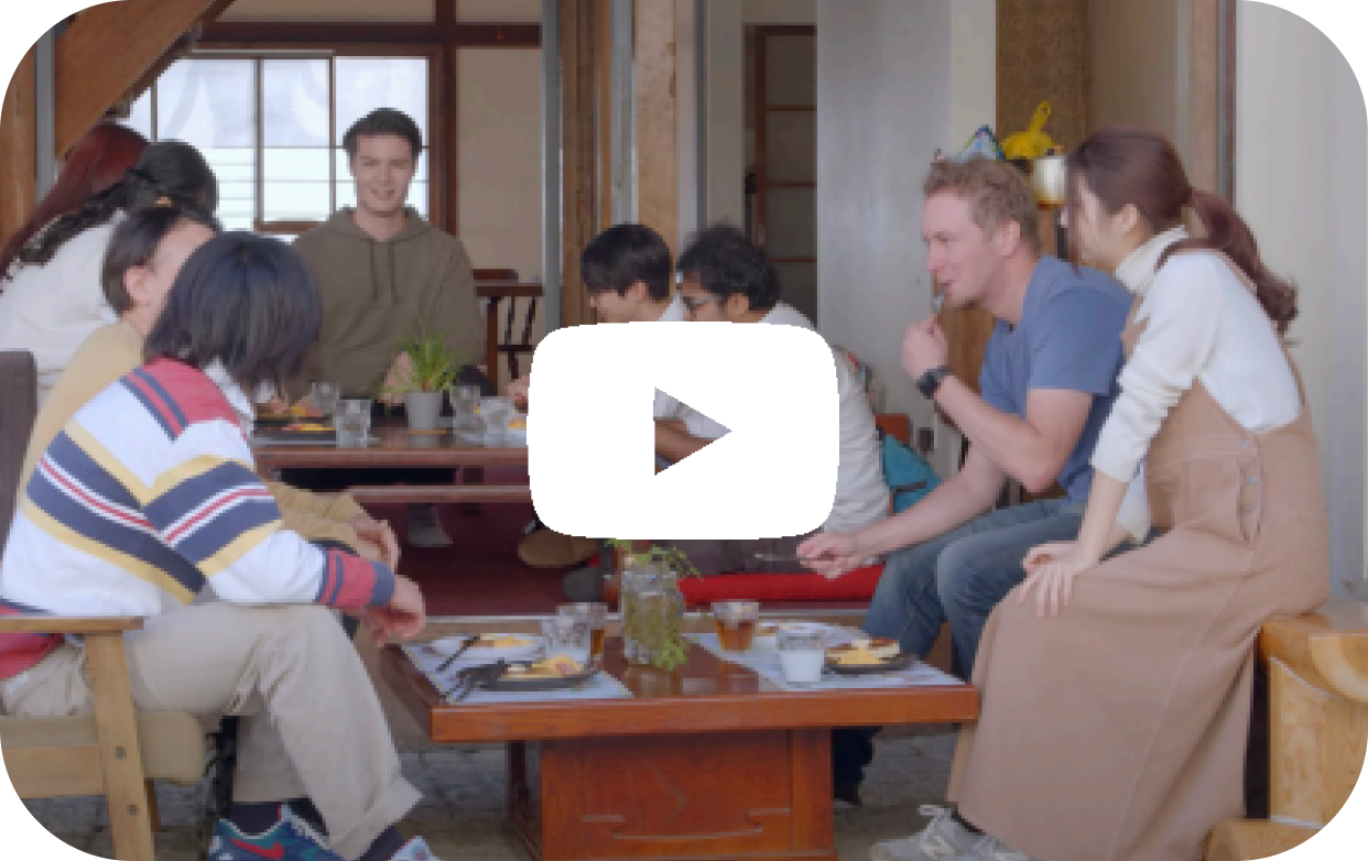室内で外国人と日本人がテーブルを囲み、会話を楽しんでいる様子。CASACOの国際交流活動を紹介する動画のサムネイル