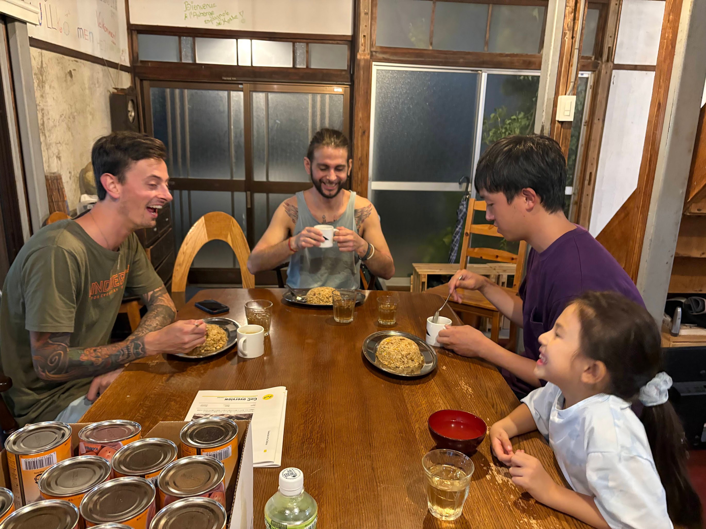 古民家の食卓で、国内外のメンバーと子どもが食事をしながら和やかに交流している様子