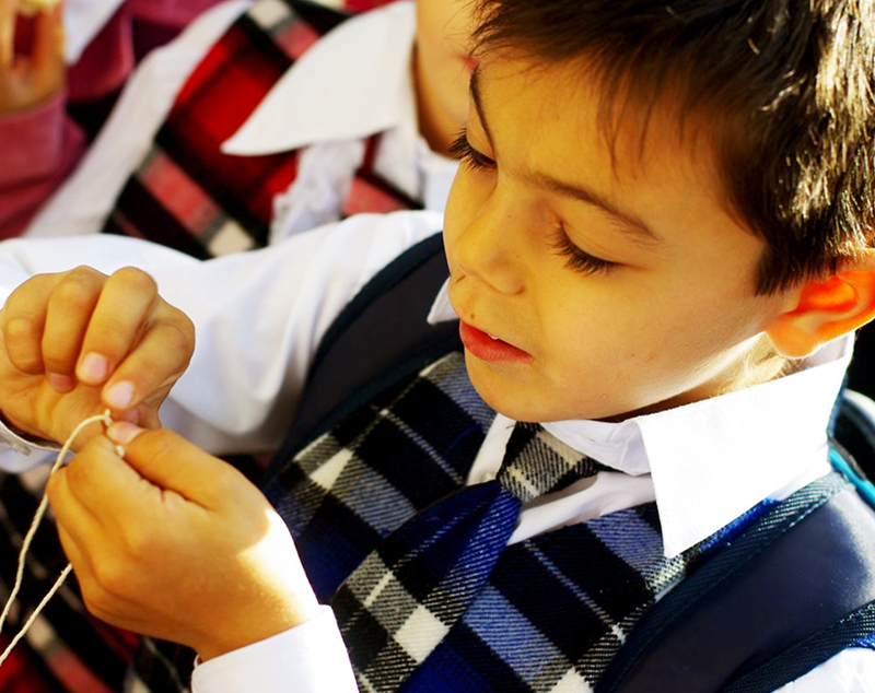 教室で笑顔を見せる4人の子どもたちが机に並んでポーズをとっている様子