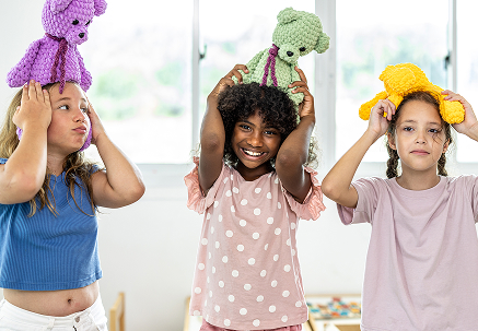 2人の子どもがぬいぐるみを頭にのせて遊んでいる様子。楽しそうに笑う表情が印象的なシーン