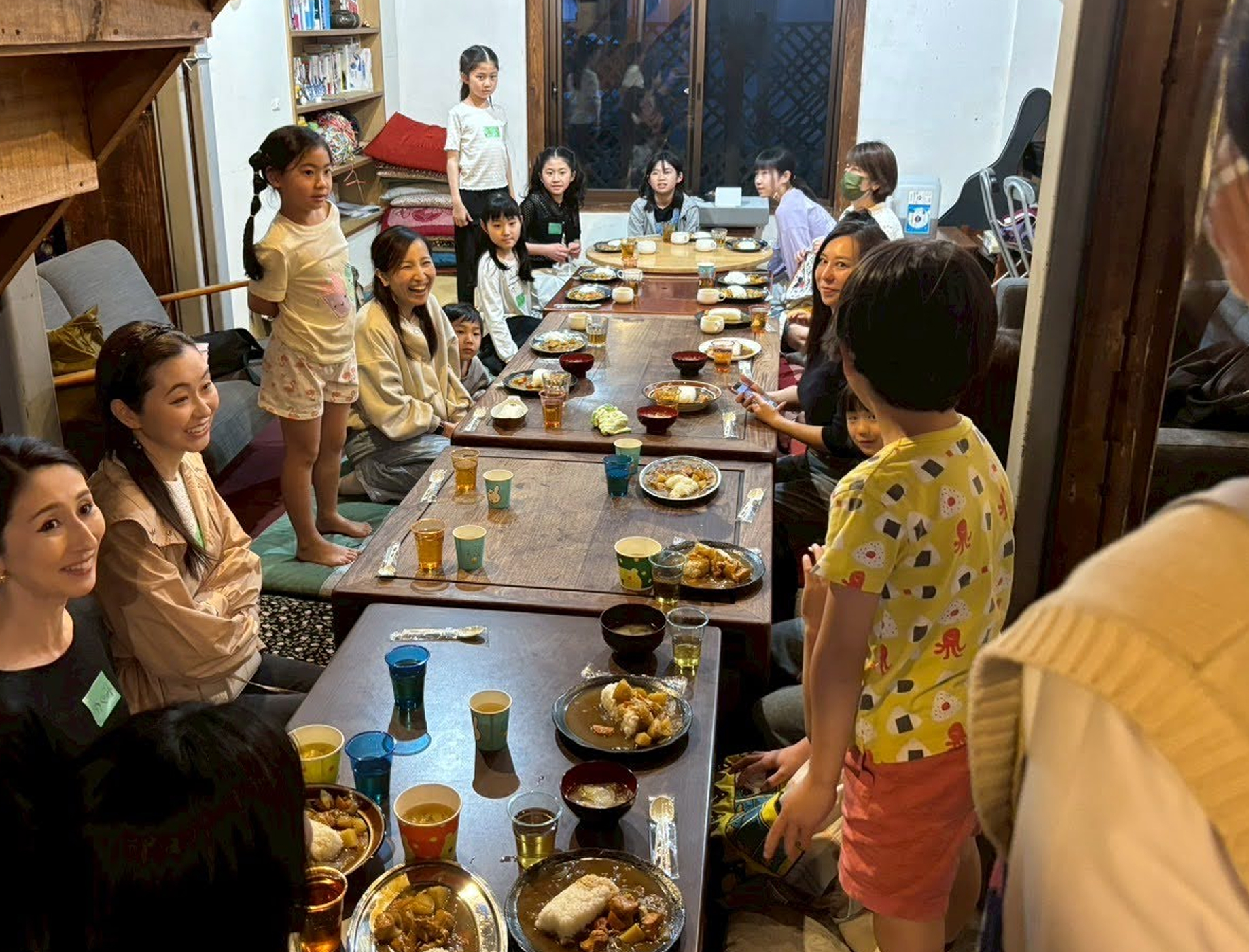 食卓を囲んでこどもたちと大人が会話をしながら食事をしている様子